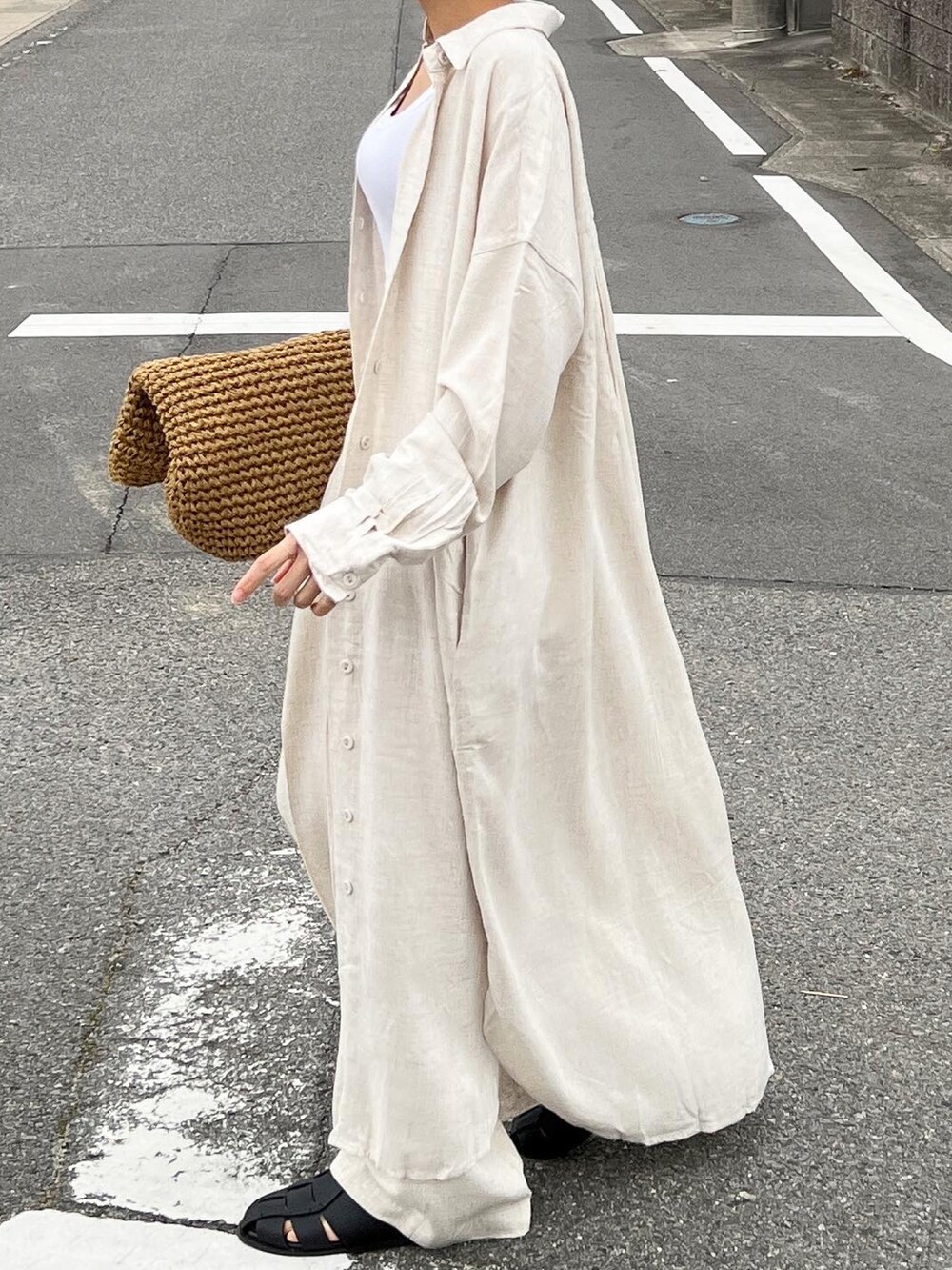 ベージュ系のかごバッグ、ベージュ系のシャツワンピース、ブラック系のサンダルを着用したレディースの春コーディネートの3枚目の写真