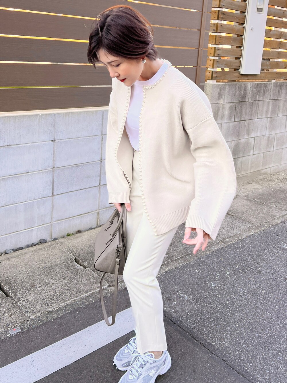 ホワイト系のカーディガン/ボレロ、グレー系のスニーカー、グレー系のハンドバッグを着用したレディースの冬コーディネートの4枚目の写真