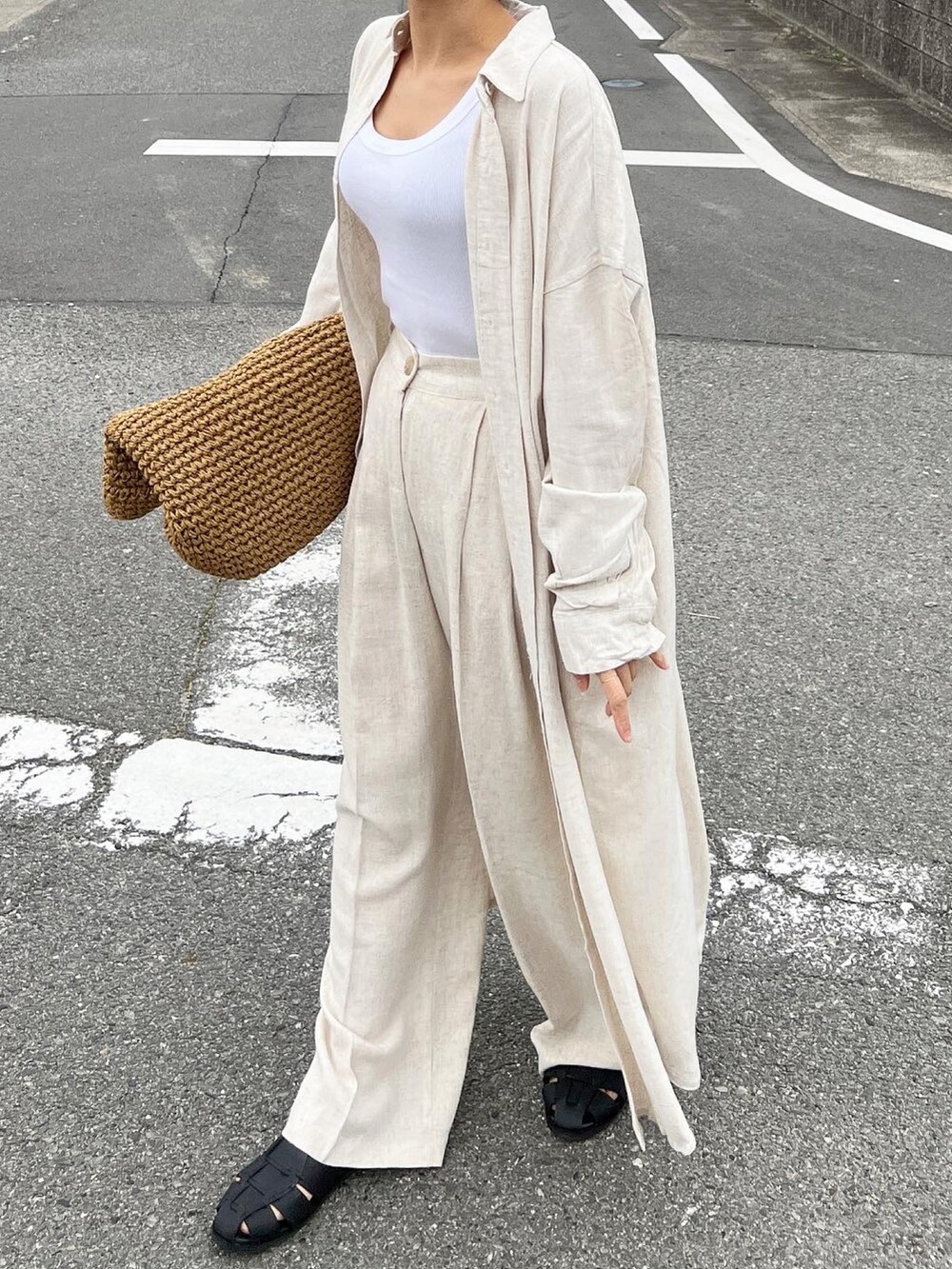 ベージュ系のかごバッグ、ベージュ系のシャツワンピース、ブラック系のサンダルを着用したレディースの春コーディネートの5枚目の写真