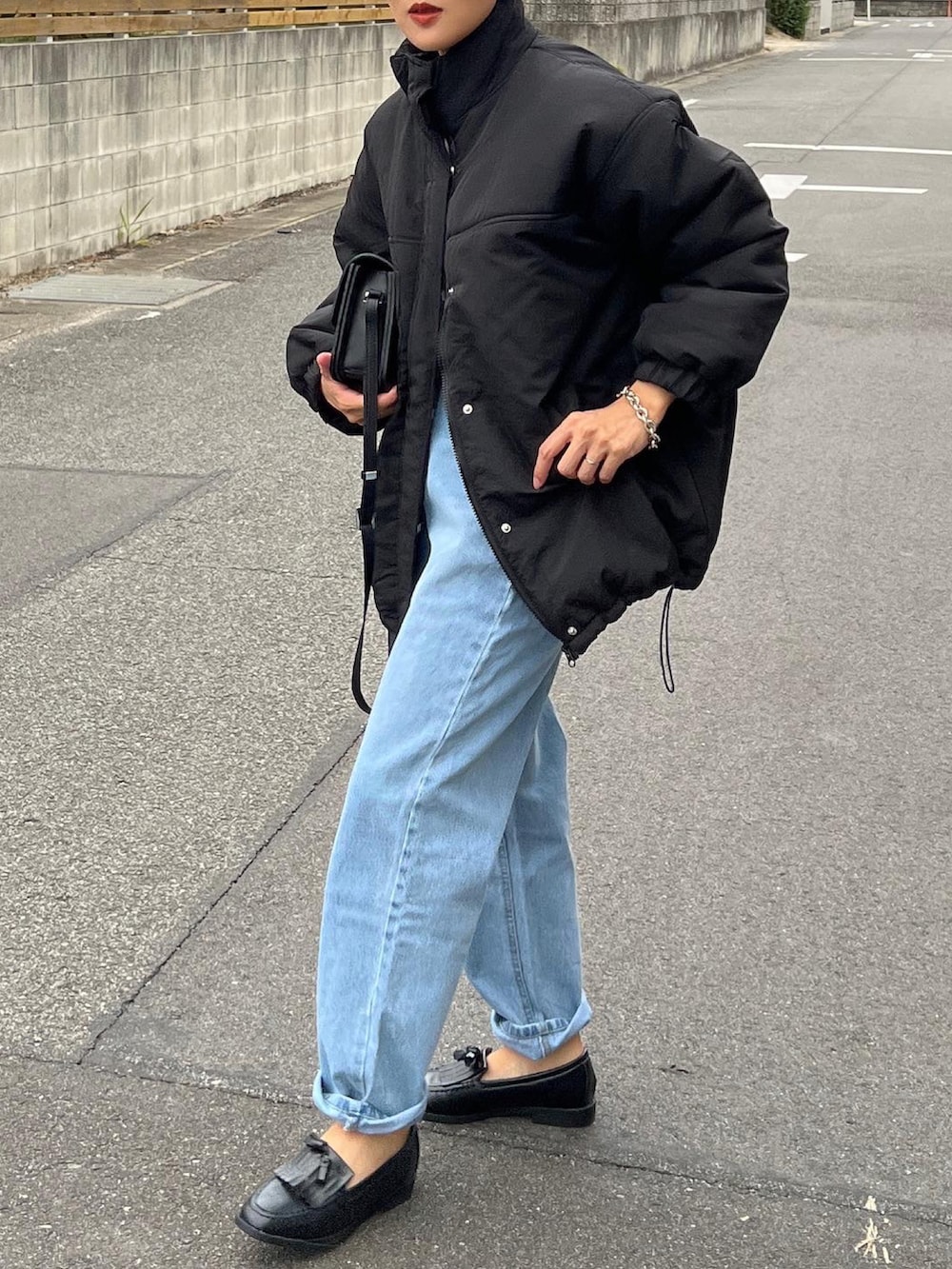 ブラック系のダウンジャケット/コート、ブラック系のショルダーバッグ、ブラック系のローファーを着用したレディースの秋コーディネートの2枚目の写真