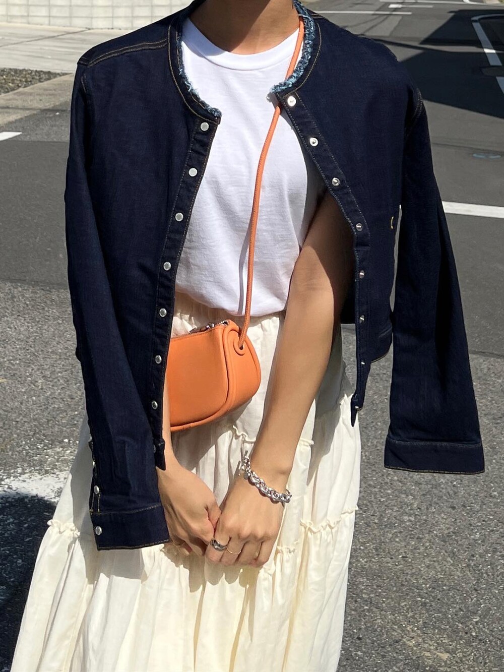 ブルー系のデニムジャケット、ホワイト系のTシャツ/カットソー、ホワイト系のスカートを着用したレディースの春コーディネートの3枚目の写真