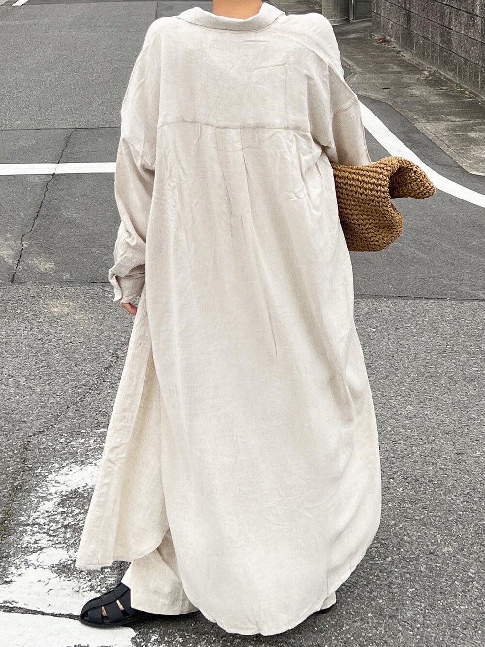 ベージュ系のかごバッグ、ベージュ系のシャツワンピース、ブラック系のサンダルを着用したレディースの春コーディネートの4枚目の写真