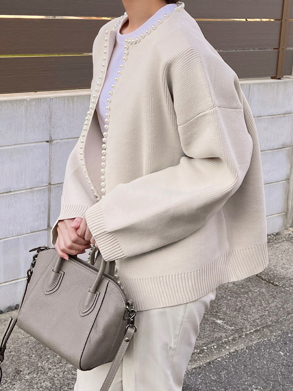 ホワイト系のカーディガン/ボレロ、グレー系のスニーカー、グレー系のハンドバッグを着用したレディースの冬コーディネートの3枚目の写真