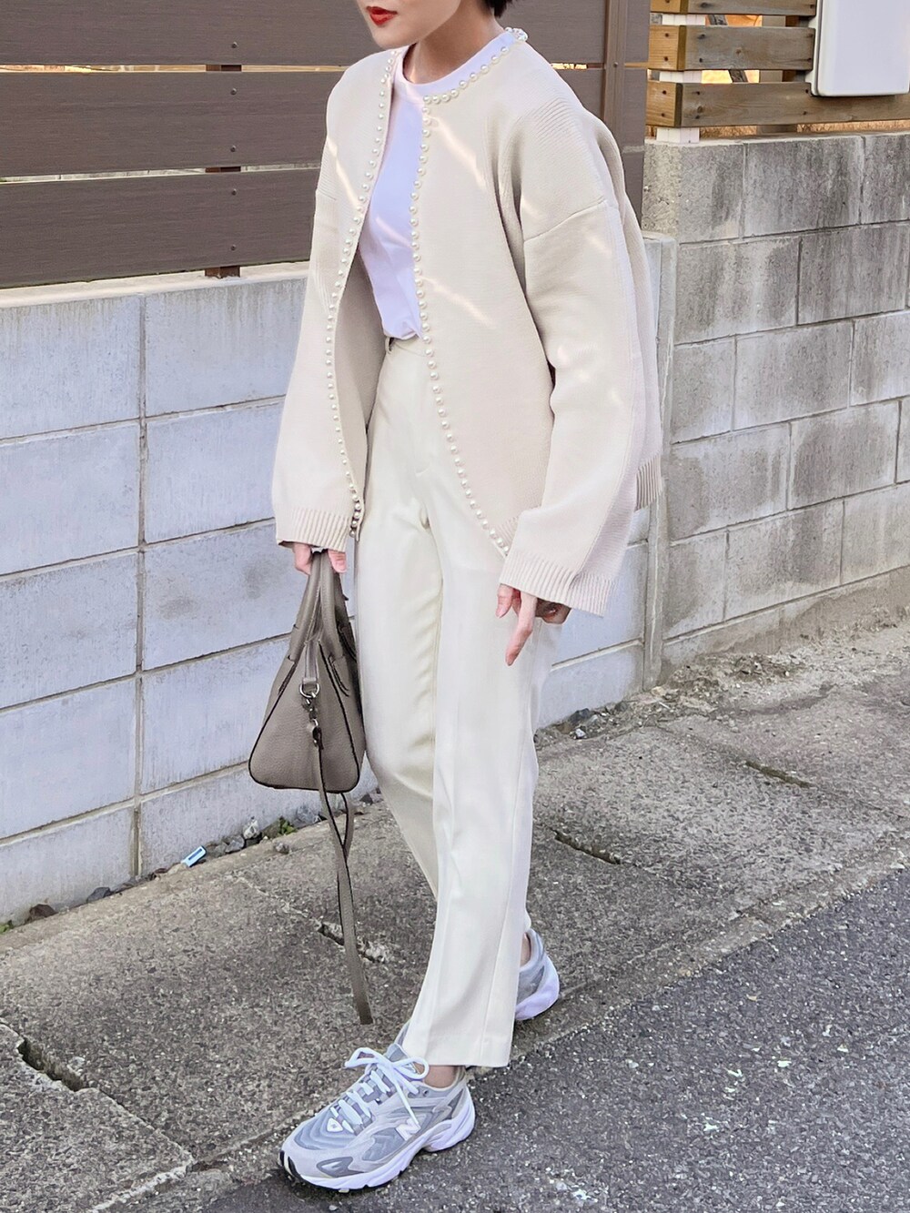 ホワイト系のカーディガン/ボレロ、グレー系のスニーカー、グレー系のハンドバッグを着用したレディースの冬コーディネートの2枚目の写真