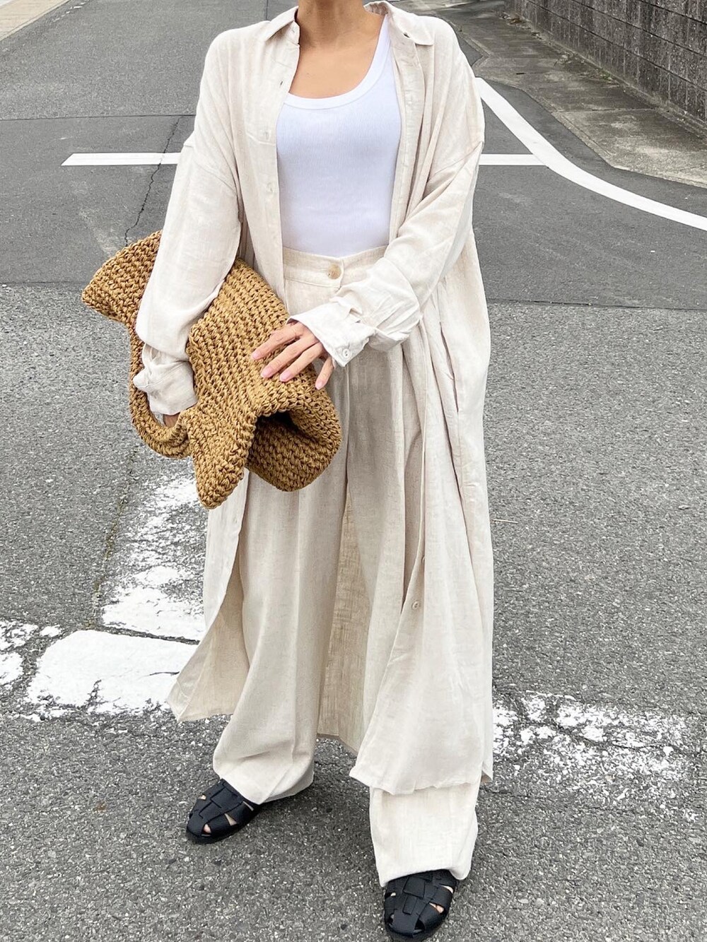 ベージュ系のかごバッグ、ベージュ系のシャツワンピース、ブラック系のサンダルを着用したレディースの春コーディネートの2枚目の写真