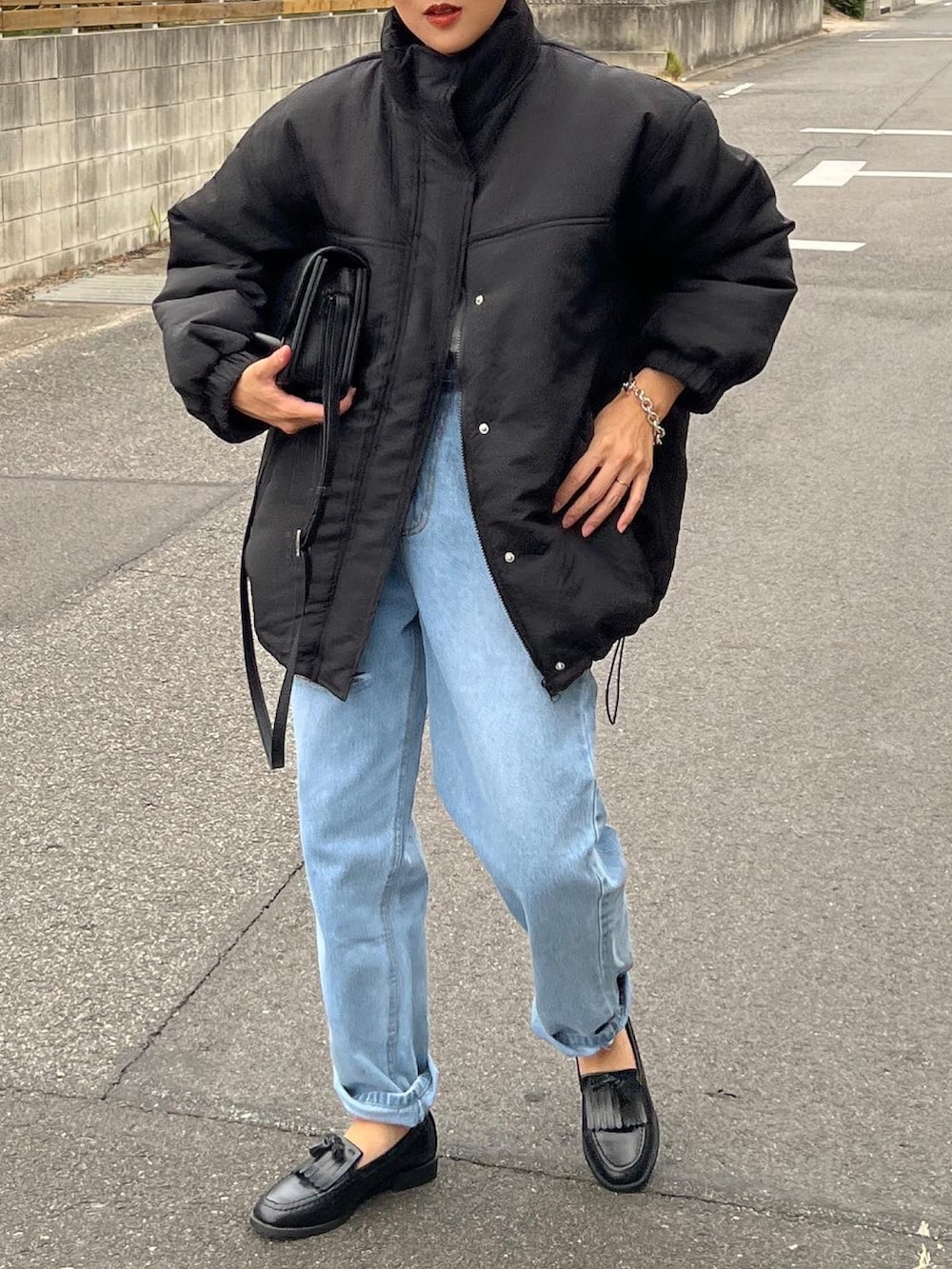 ブラック系のダウンジャケット/コート、ブラック系のショルダーバッグ、ブラック系のローファーを着用したレディースの秋コーディネートの3枚目の写真