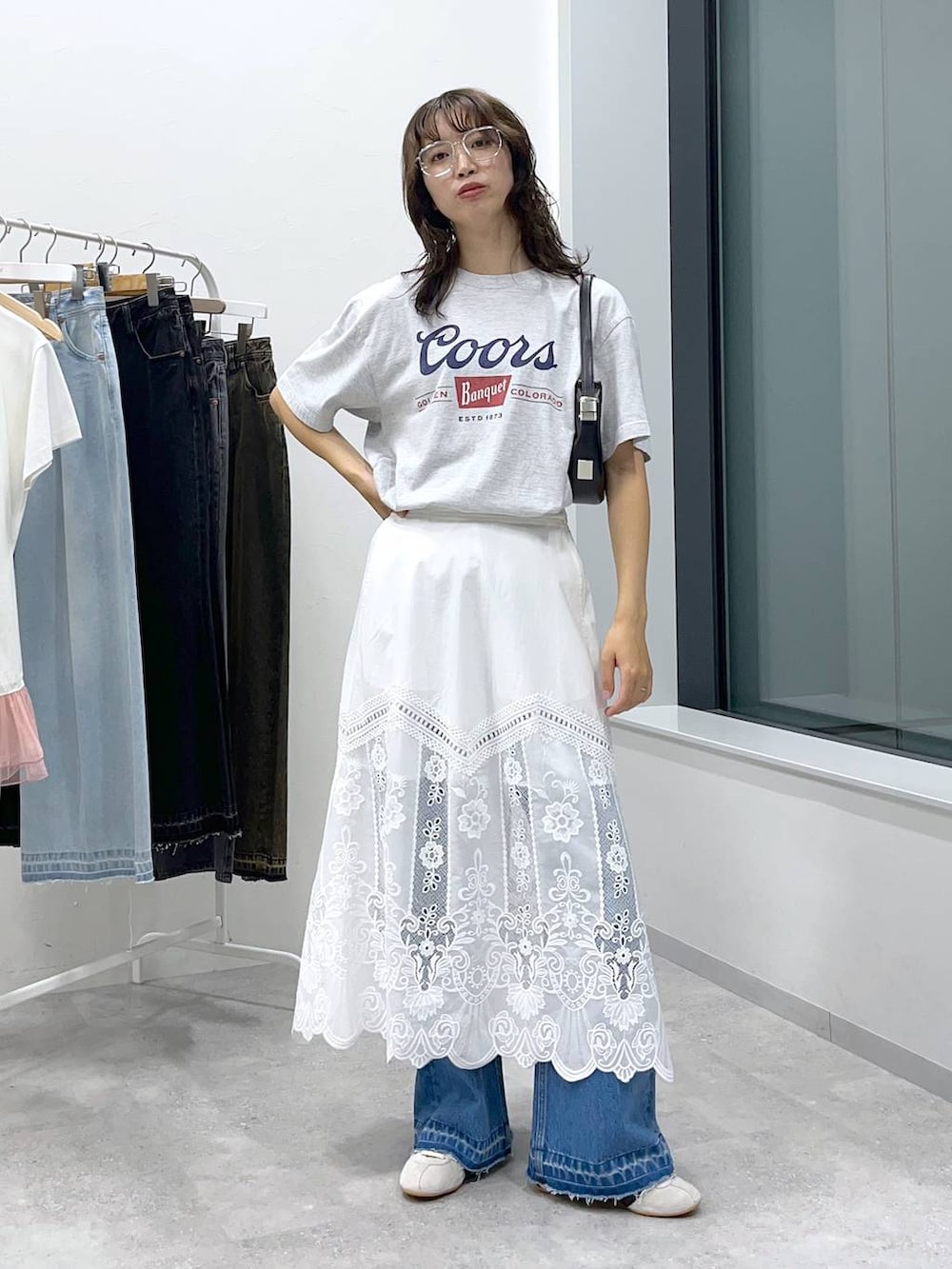 ブラック系のショルダーバッグ、ブルー系のデニムパンツ、その他のTシャツ/カットソーを着用したレディースの夏コーディネートの2枚目の写真