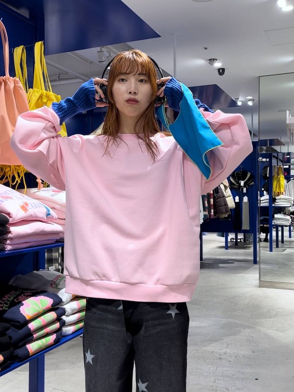 ブルー系のトートバッグ、ブラック系のデニムパンツ、ピンク系のスウェットを着用したレディースの冬コーディネートの3枚目の写真