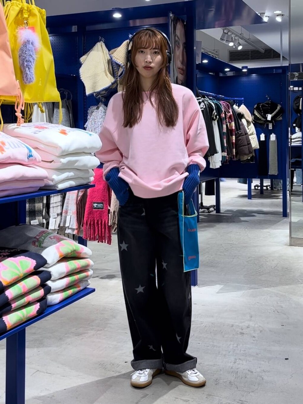 ブルー系のトートバッグ、ブラック系のデニムパンツ、ピンク系のスウェットを着用したレディースの冬コーディネートの2枚目の写真