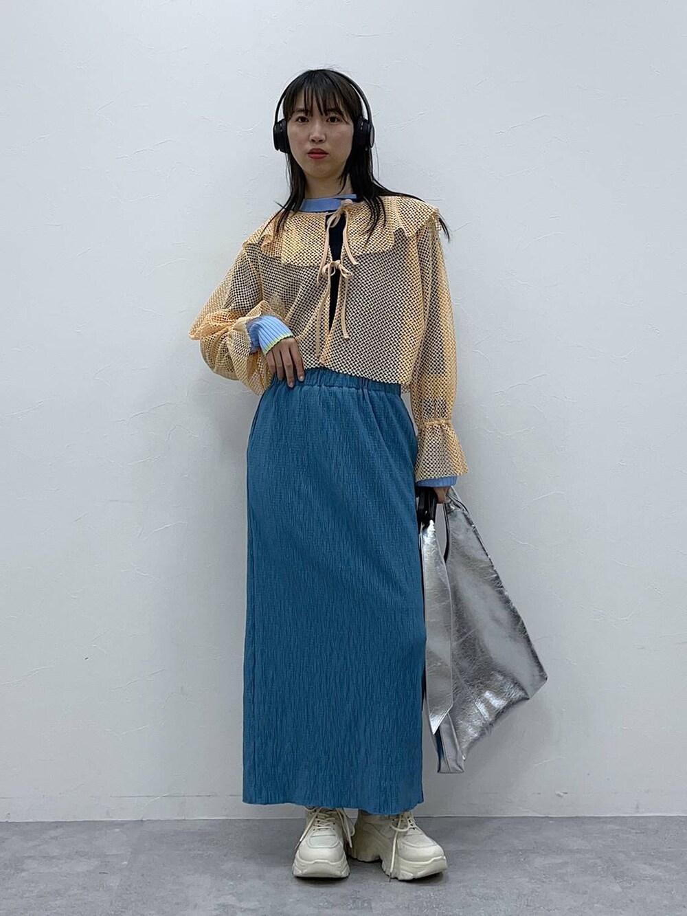ブルー系のニット/セーター、ブルー系のスカート、シルバー系のトートバッグを着用したレディースの春コーディネートの2枚目の写真