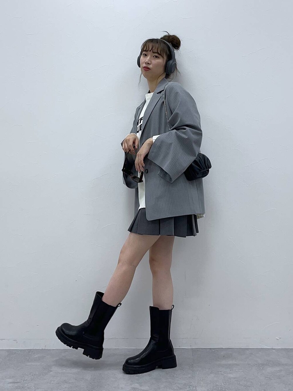 グレー系のテーラードジャケット、ホワイト系のニット/セーター、ブラック系のブーツを着用したレディースの春コーディネートの2枚目の写真