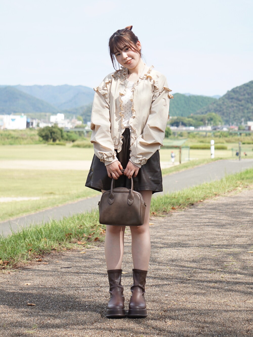 ベージュ系のノーカラージャケット、ホワイト系のタンクトップ、ブラウン系のその他パンツを着用したレディースの秋コーディネートの2枚目の写真