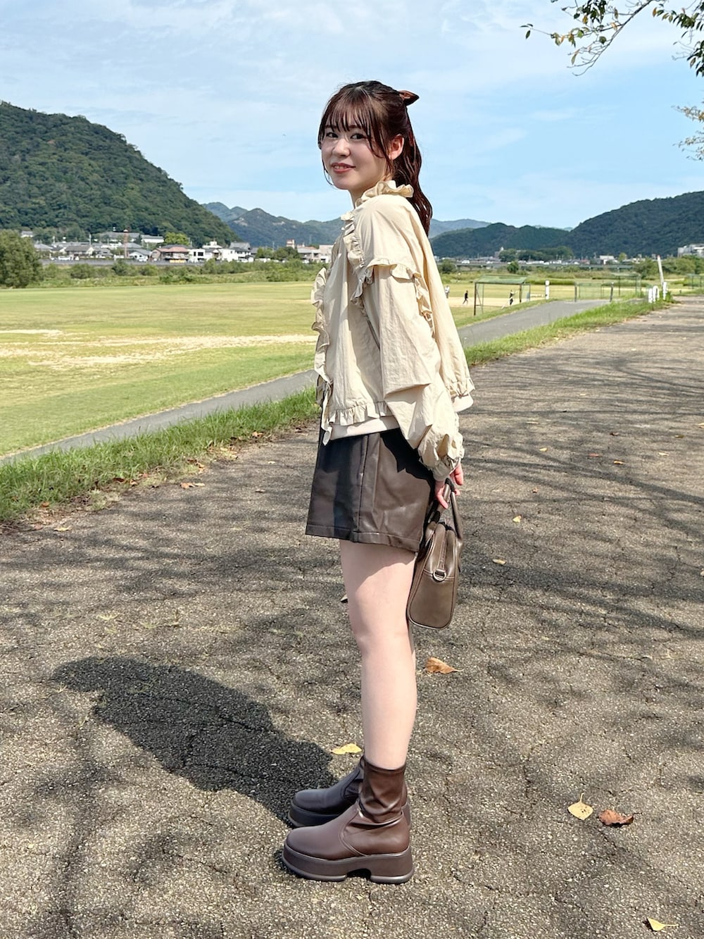 ベージュ系のノーカラージャケット、ホワイト系のタンクトップ、ブラウン系のその他パンツを着用したレディースの秋コーディネートの3枚目の写真