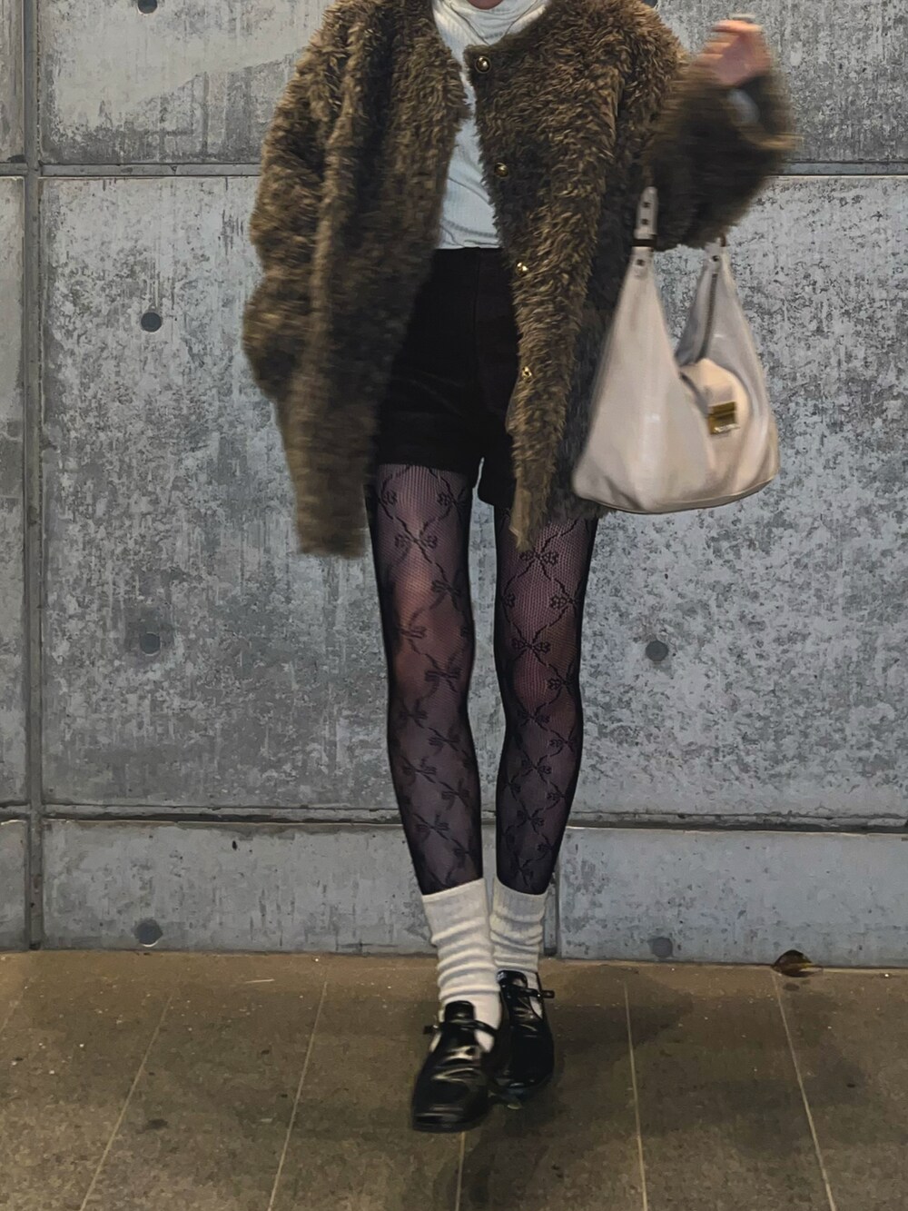 ブラウン系のノーカラーコート、ベージュ系のショルダーバッグ、ホワイト系のソックス/靴下を着用したレディースの冬コーディネートの2枚目の写真