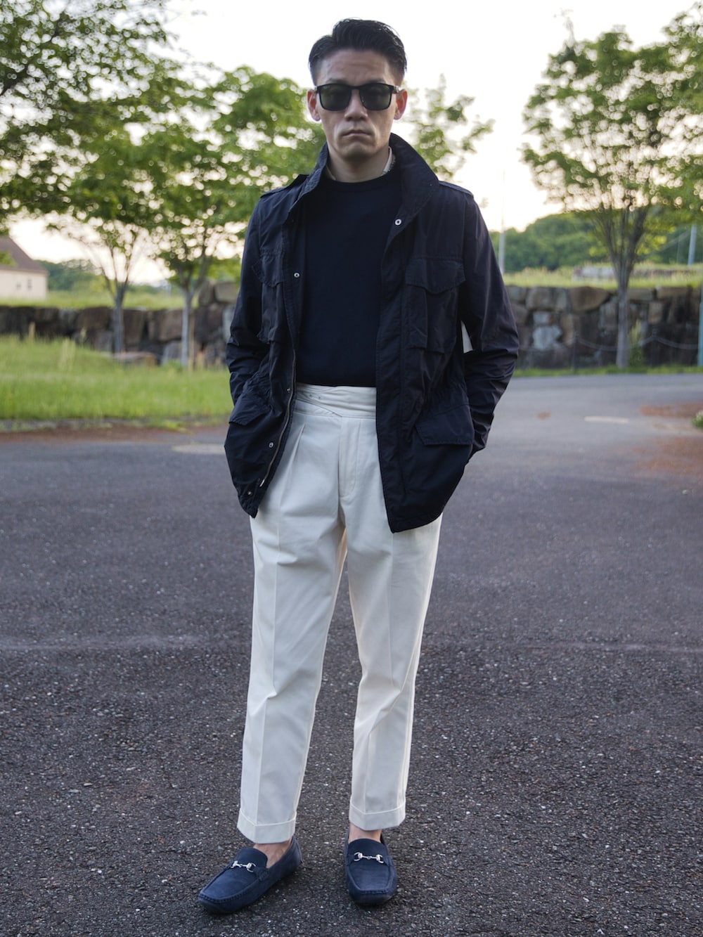 ホワイト系のスラックス、ブルー系のミリタリージャケット、ブルー系のニット/セーターを着用したメンズの春コーディネートの2枚目の写真