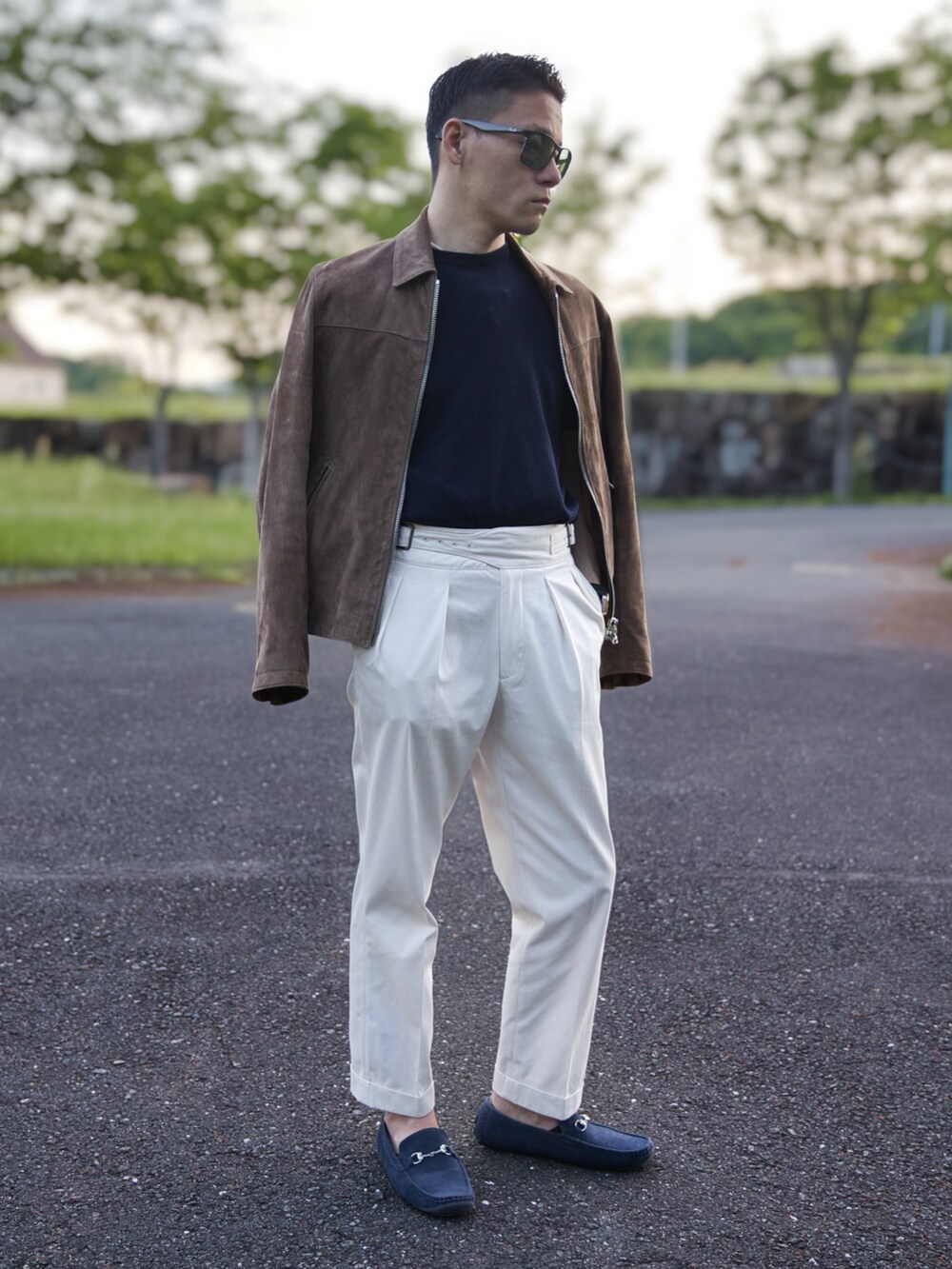 ベージュ系のライダースジャケット、ホワイト系のスラックス、ブルー系のニット/セーターを着用したメンズの春コーディネートの2枚目の写真