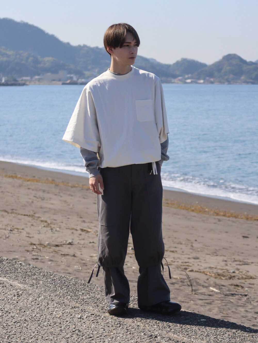 ホワイト系のTシャツ/カットソー、グレー系のカーゴパンツ、ブラック系のスニーカーを着用したメンズの春コーディネートの2枚目の写真