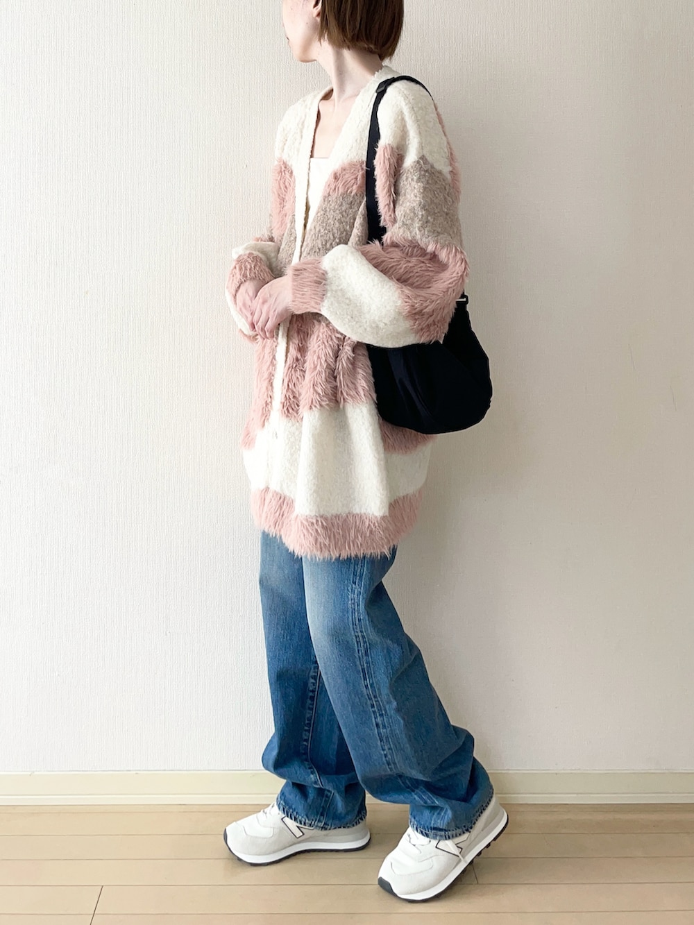 ホワイト系のカーディガン/ボレロ、ホワイト系のスニーカー、ブルー系のデニムパンツを着用したレディースの秋コーディネートの2枚目の写真