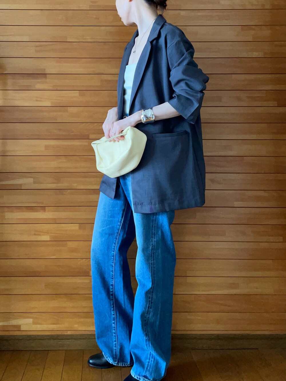 グレー系のテーラードジャケット、ホワイト系のキャミソール、ブルー系のデニムパンツを着用したレディースの夏コーディネートの2枚目の写真