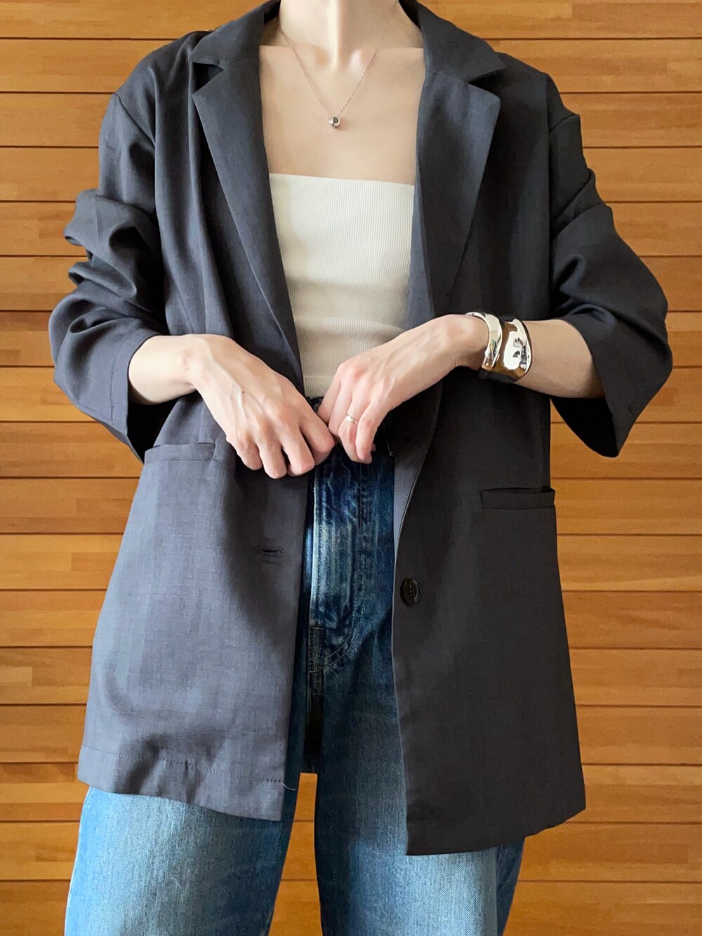 グレー系のテーラードジャケット、ホワイト系のキャミソール、ブルー系のデニムパンツを着用したレディースの夏コーディネートの3枚目の写真