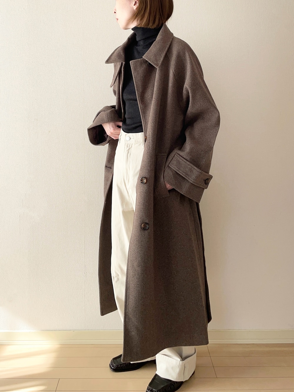 ブラウン系のステンカラーコート、ブラック系のニット/セーター、ホワイト系のその他パンツを着用したレディースの秋コーディネートの2枚目の写真