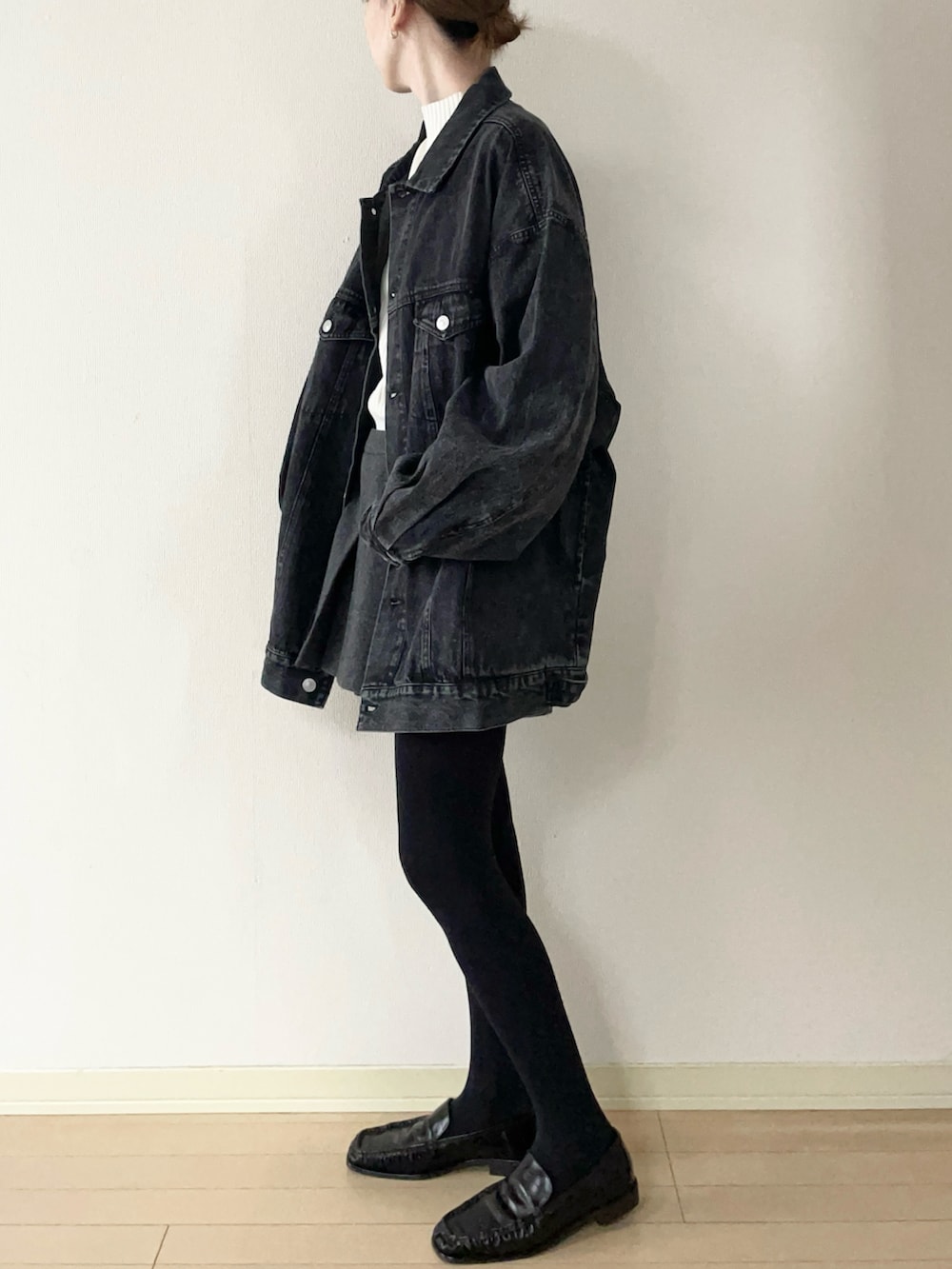 ブラック系のデニムジャケット、ブラウン系のローファー、ホワイト系のニット/セーターを着用したレディースの冬コーディネートの2枚目の写真