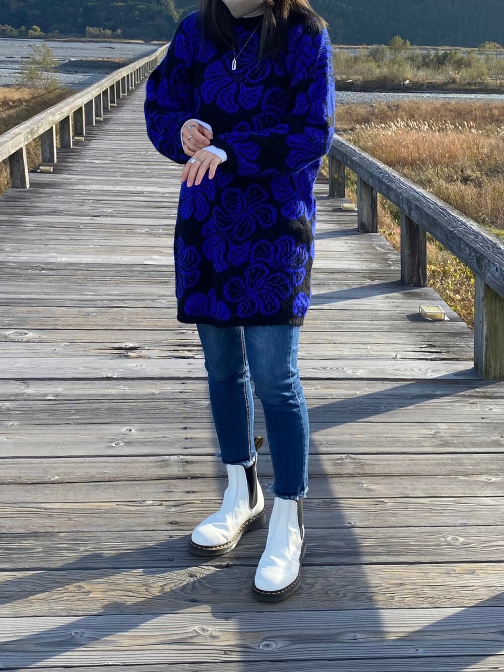 ホワイト系のトップス、ブルー系のデニムパンツ、ホワイト系のブーツを着用したレディースの秋コーディネートの2枚目の写真