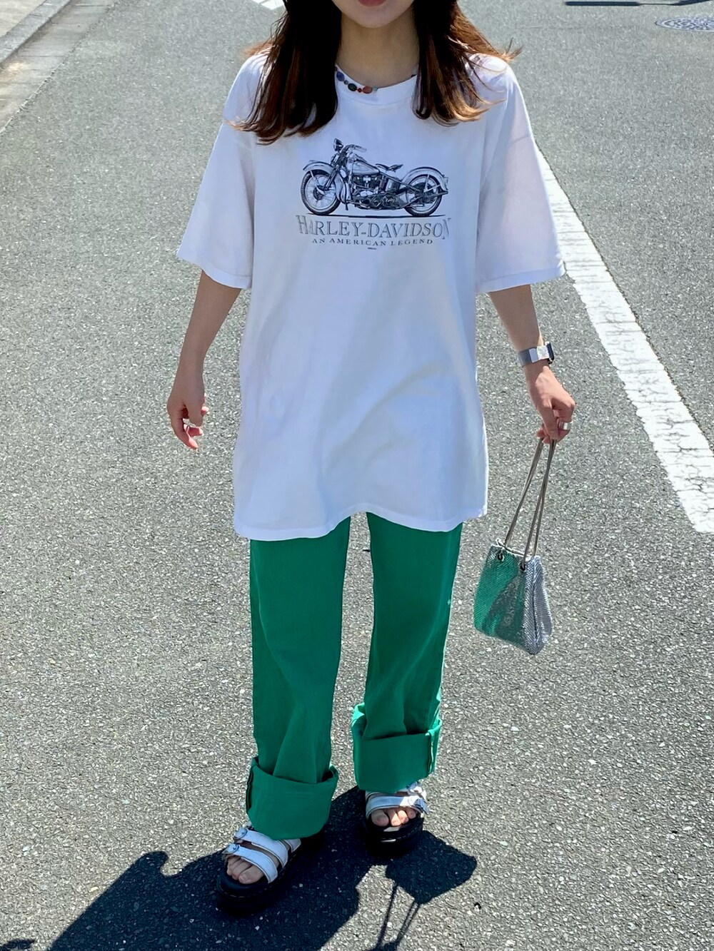 ホワイト系のTシャツ/カットソー、シルバー系のショルダーバッグ、グリーン系のデニムパンツを着用したレディースの夏コーディネートの2枚目の写真