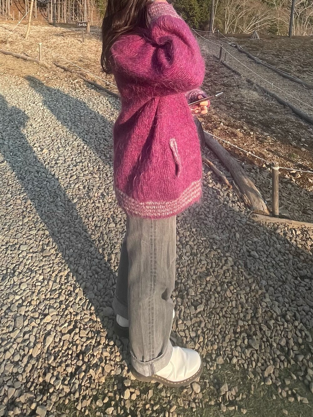 ブラック系のハンドバッグ、グレー系のデニムパンツ、ホワイト系のブーツを着用したレディースの春コーディネートの2枚目の写真