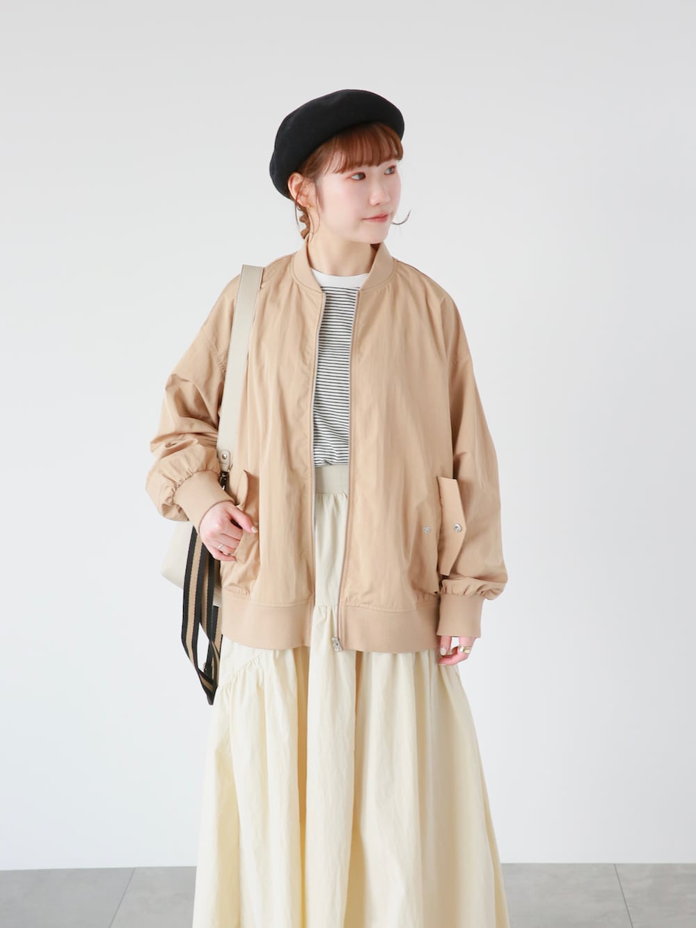 ベージュ系のスカート、ホワイト系のハンドバッグ、ホワイト系のドレスシューズを着用したレディースの春コーディネートの2枚目の写真