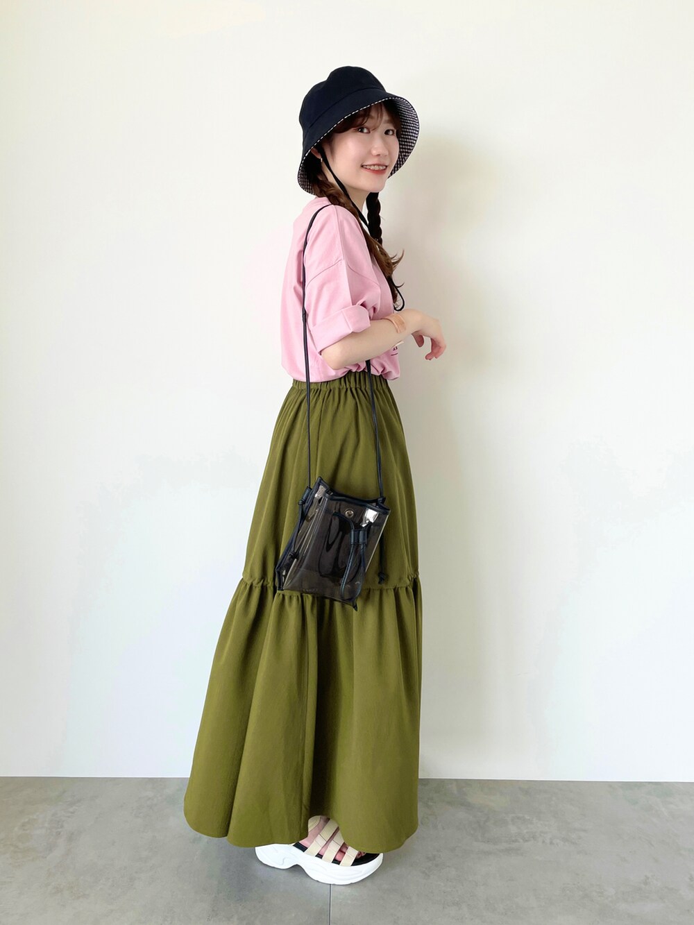 ピンク系のTシャツ/カットソー、グリーン系のスカート、ブラック系のハンドバッグを着用したレディースの春コーディネートの2枚目の写真