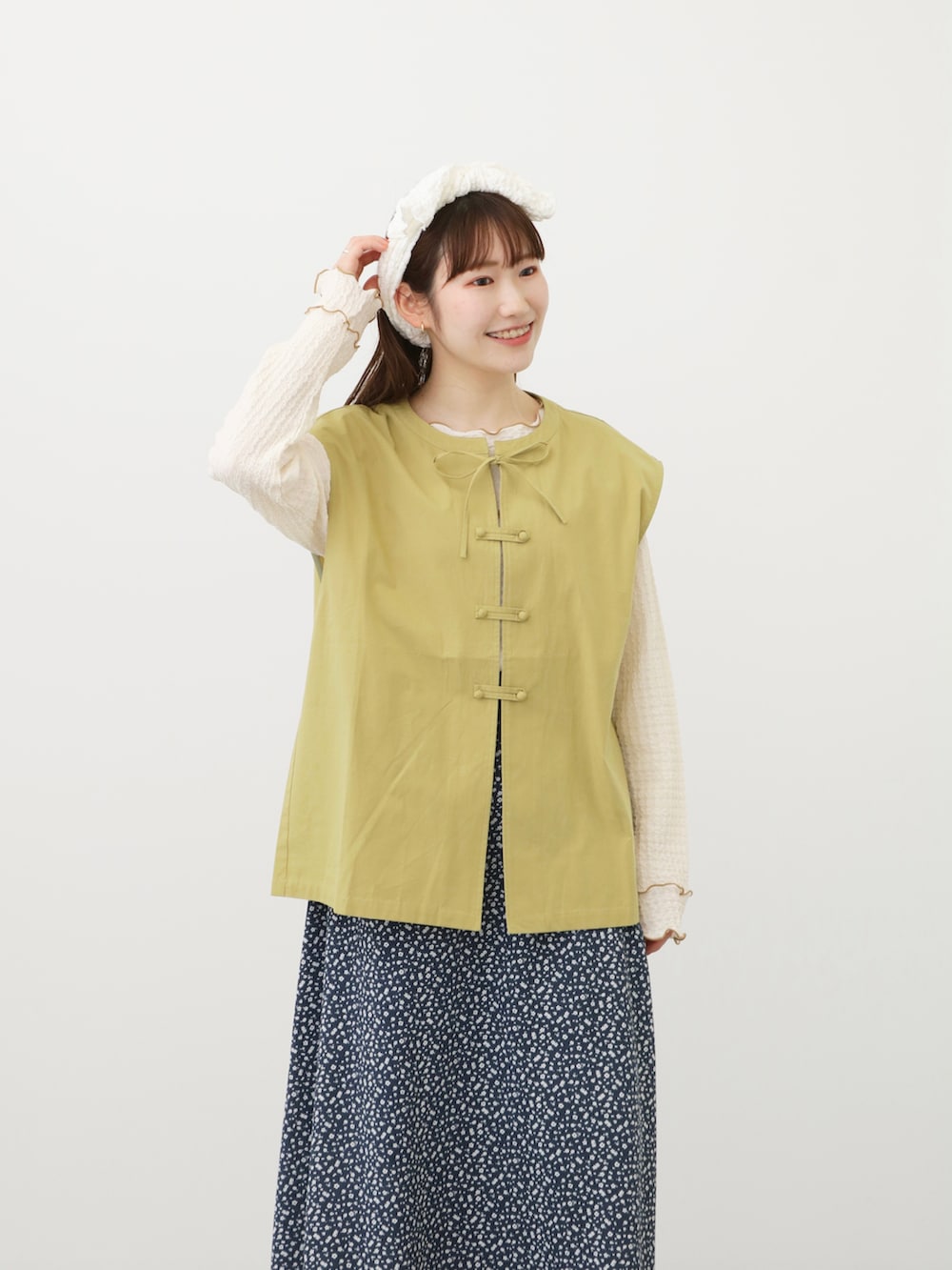 ブラウン系のその他シューズ、グリーン系のベスト、ブルー系のスカートを着用したレディースの春コーディネートの2枚目の写真