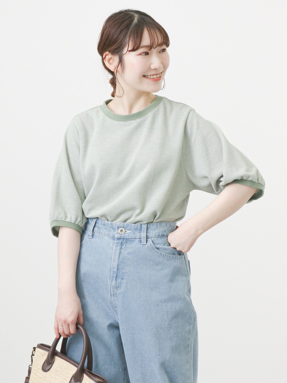 グリーン系のTシャツ/カットソー、ブルー系のデニムパンツ、ブラウン系のハンドバッグを着用したレディースの春コーディネートの2枚目の写真