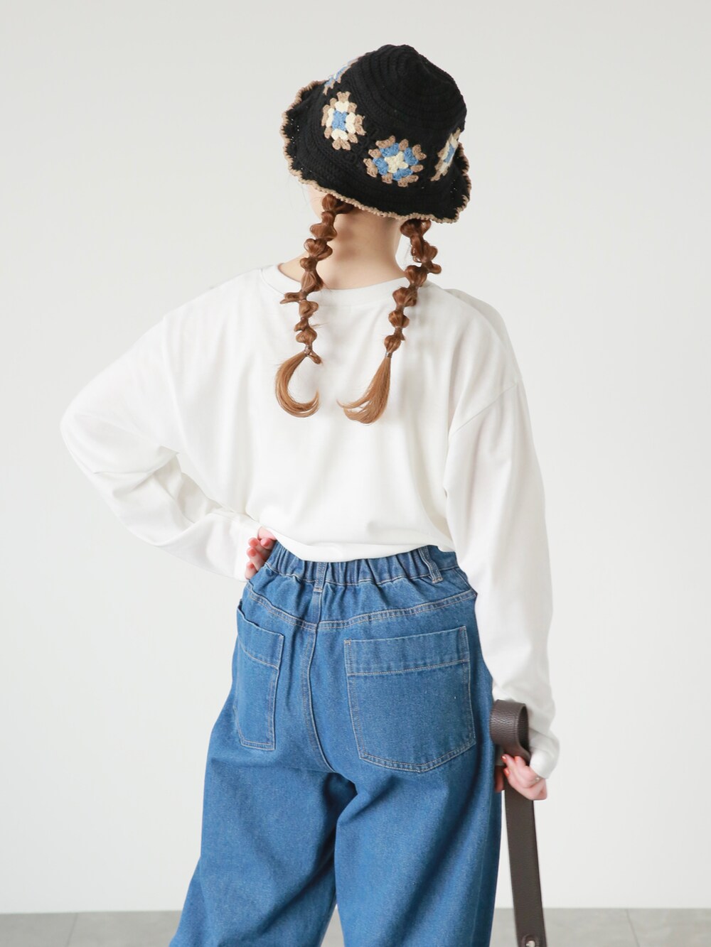 ブルー系のデニムパンツ、ブラウン系のハンドバッグ、ホワイト系のTシャツ/カットソーを着用したレディースの春コーディネートの3枚目の写真