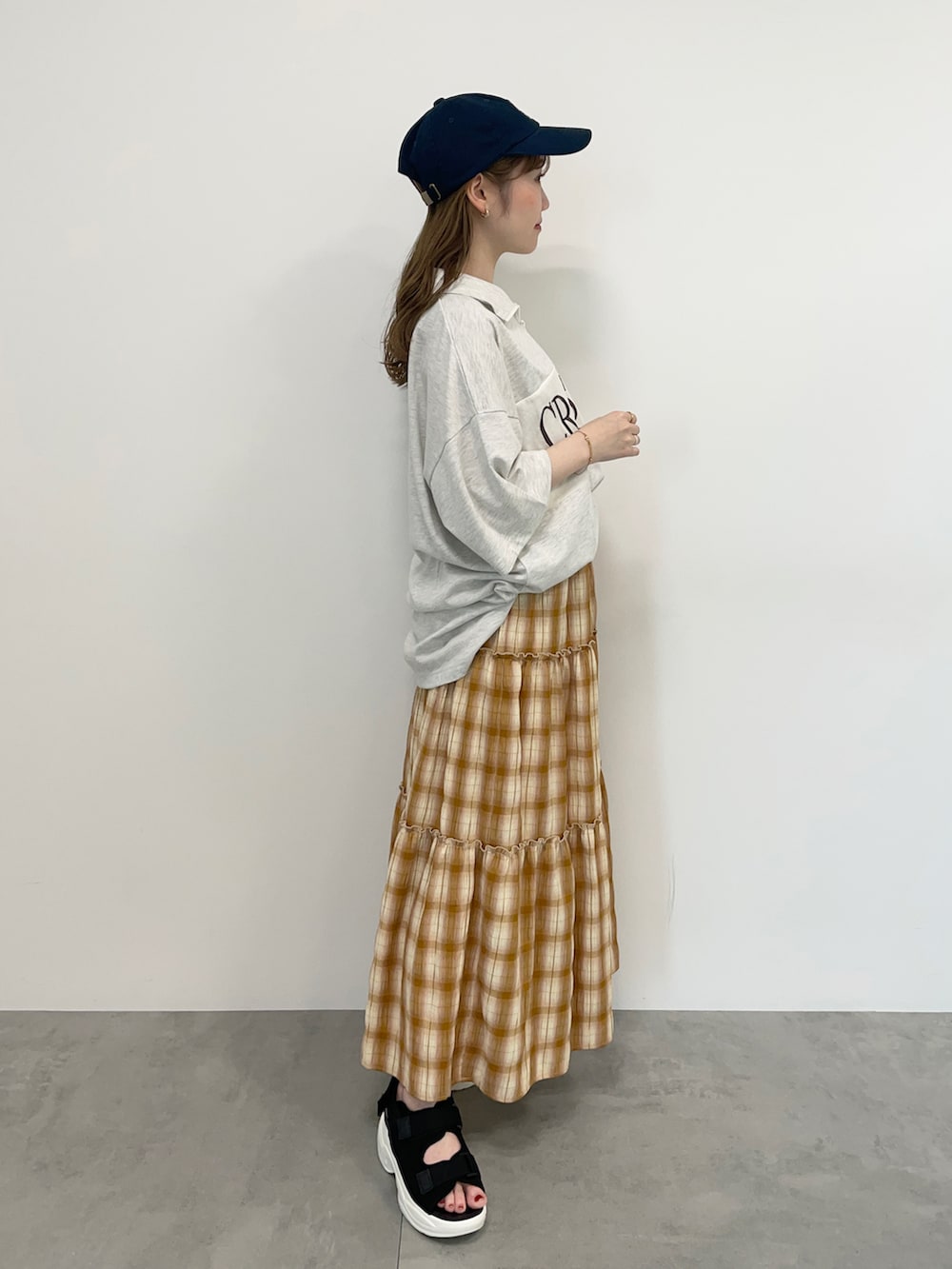 グレー系のTシャツ/カットソー、イエロー系のスカート、ブラック系のサンダルを着用したレディースの春コーディネートの2枚目の写真