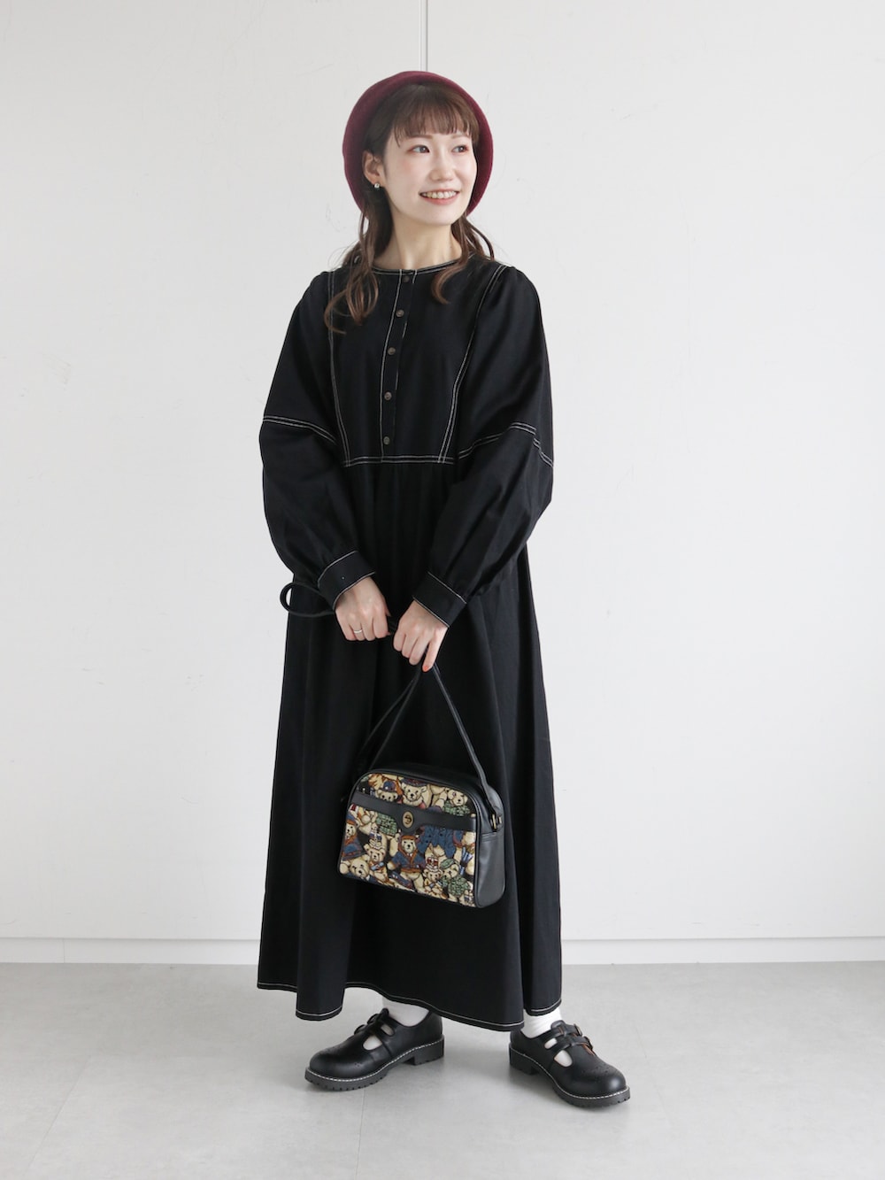 ブラック系のワンピース、ホワイト系のベスト、ブラック系のショルダーバッグを着用したレディースの秋コーディネートの2枚目の写真