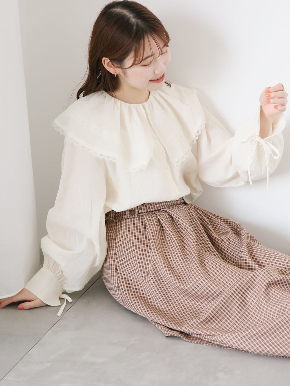 ホワイト系のシャツ/ブラウス、ブラウン系のスカート、ブラウン系のハンドバッグを着用したレディースの秋コーディネートの2枚目の写真