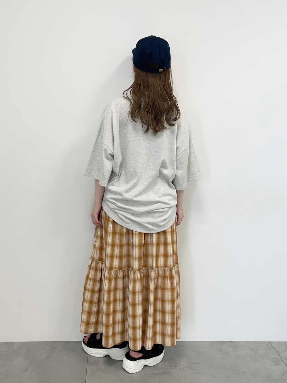 グレー系のTシャツ/カットソー、イエロー系のスカート、ブラック系のサンダルを着用したレディースの春コーディネートの3枚目の写真