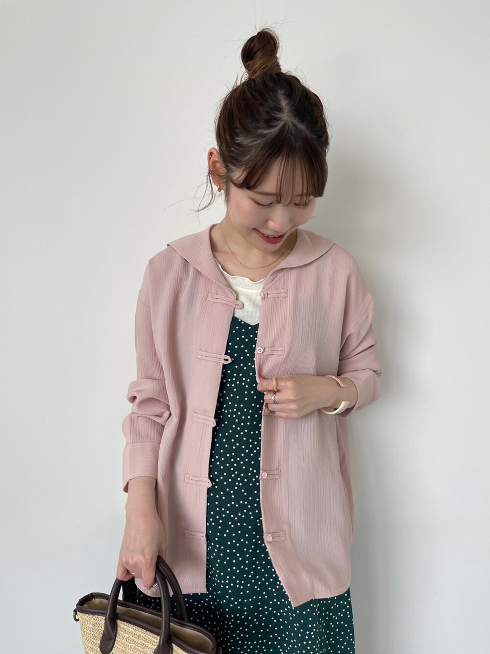 ピンク系のシャツ/ブラウス、グリーン系のワンピース、ブラウン系のハンドバッグを着用したレディースの春コーディネートの3枚目の写真