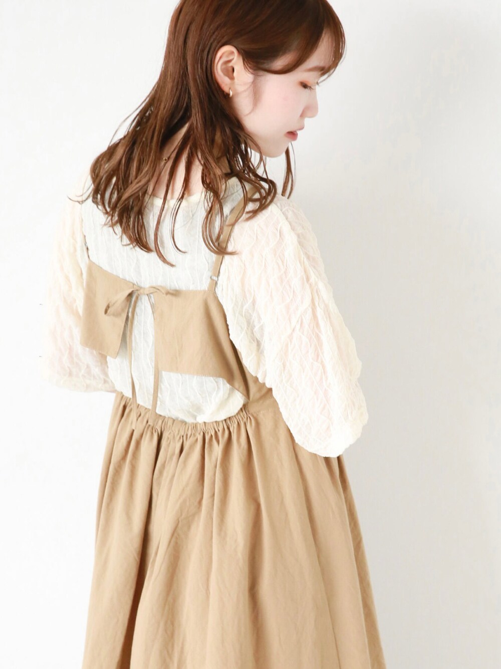 ベージュ系のワンピース、ホワイト系のTシャツ/カットソー、ブラウン系のサンダルを着用したレディースの夏コーディネートの2枚目の写真