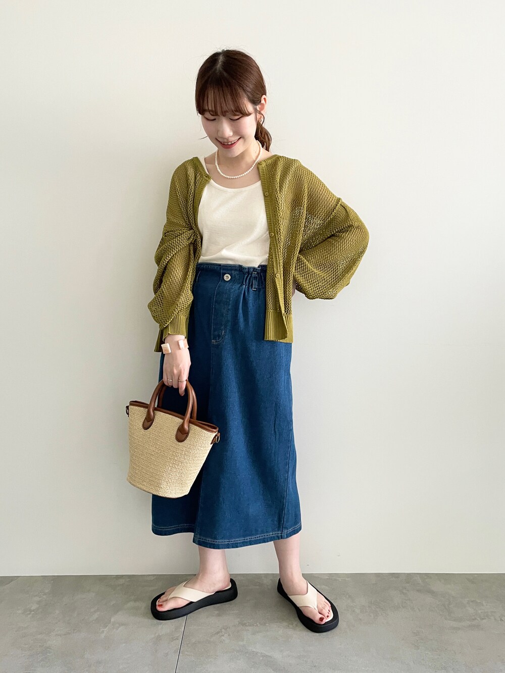 グリーン系のカーディガン/ボレロ、イエロー系のハンドバッグ、ホワイト系のタンクトップを着用したレディースの春コーディネートの2枚目の写真