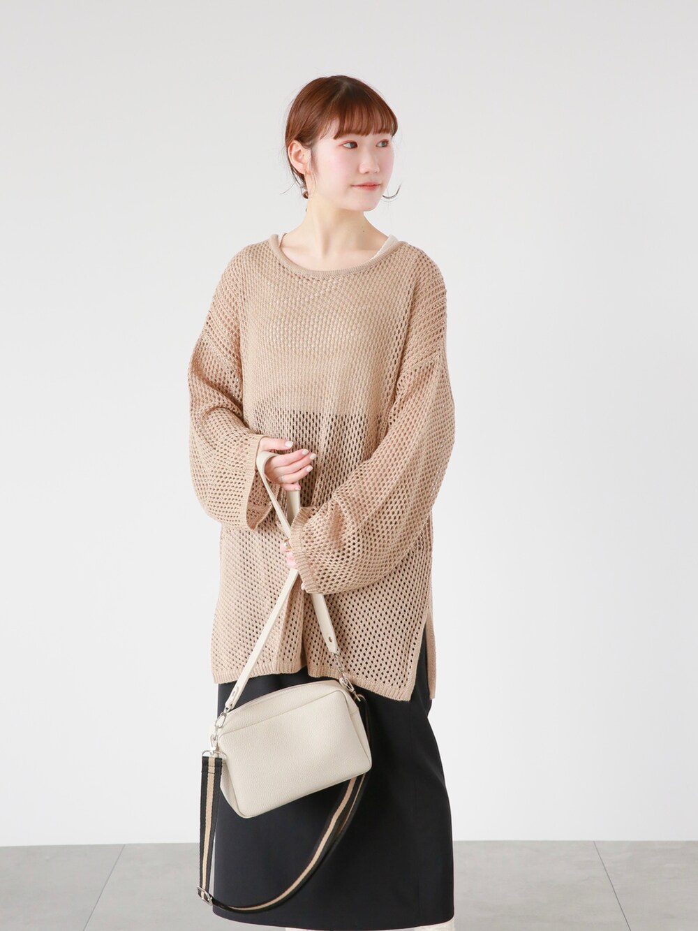 ホワイト系のタンクトップ、ベージュ系のその他トップス、ブラック系のスカートを着用したレディースの春コーディネートの2枚目の写真