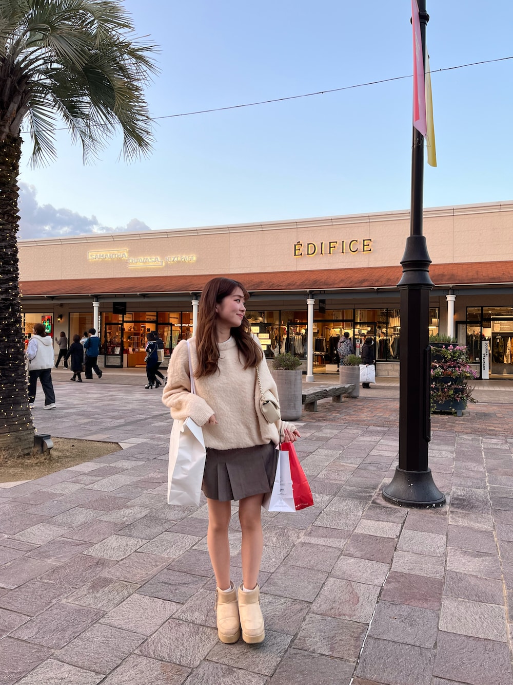 ホワイト系のニット/セーター、ブラウン系のスカート、ホワイト系のショルダーバッグを着用したレディースの冬コーディネートの2枚目の写真