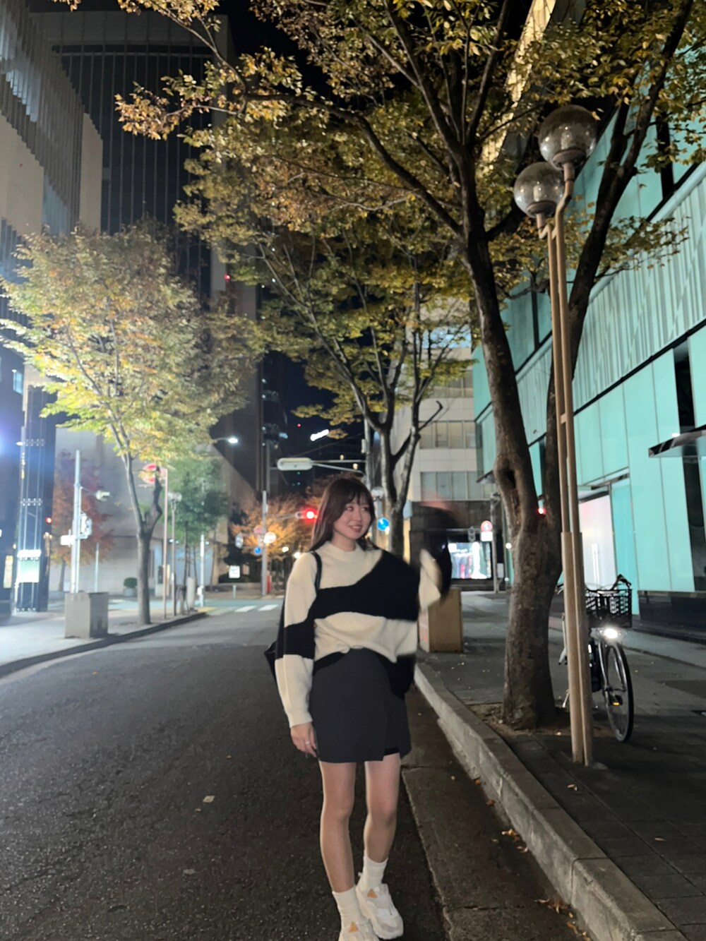 ホワイト系のニット/セーター、グレー系のスカート、ホワイト系のスニーカーを着用したレディースの冬コーディネートの2枚目の写真