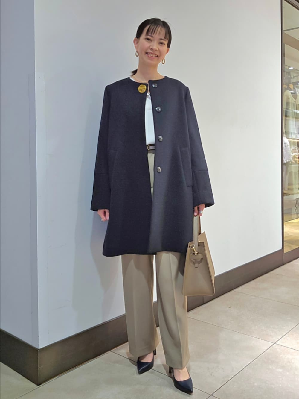 グリーン系のその他パンツ、ブルー系のノーカラーコート、ベージュ系のショルダーバッグを着用したレディースの冬コーディネートの2枚目の写真