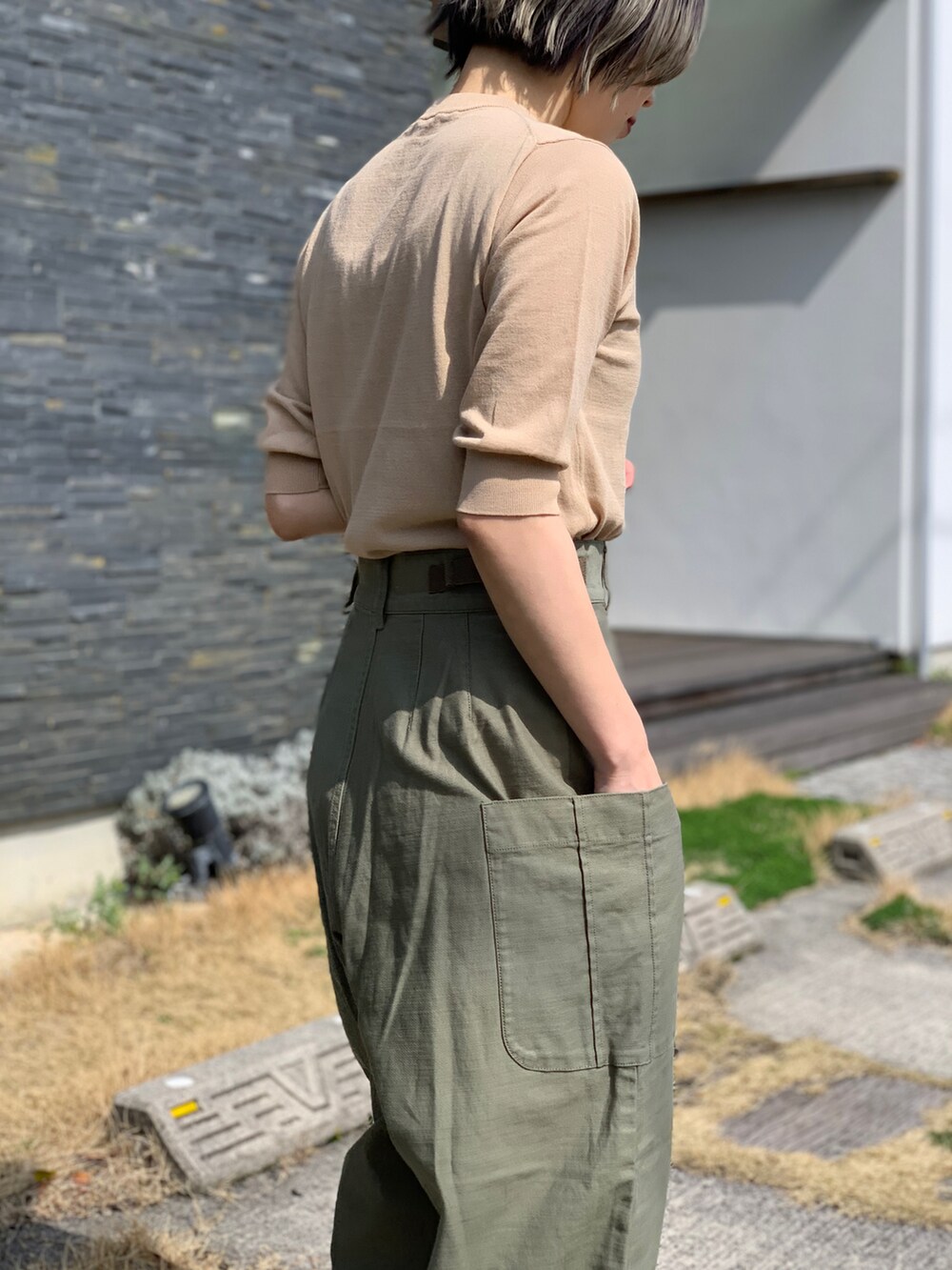 グリーン系のパンツ、ベージュ系のニット/セーターを着用したレディースの春コーディネートの2枚目の写真