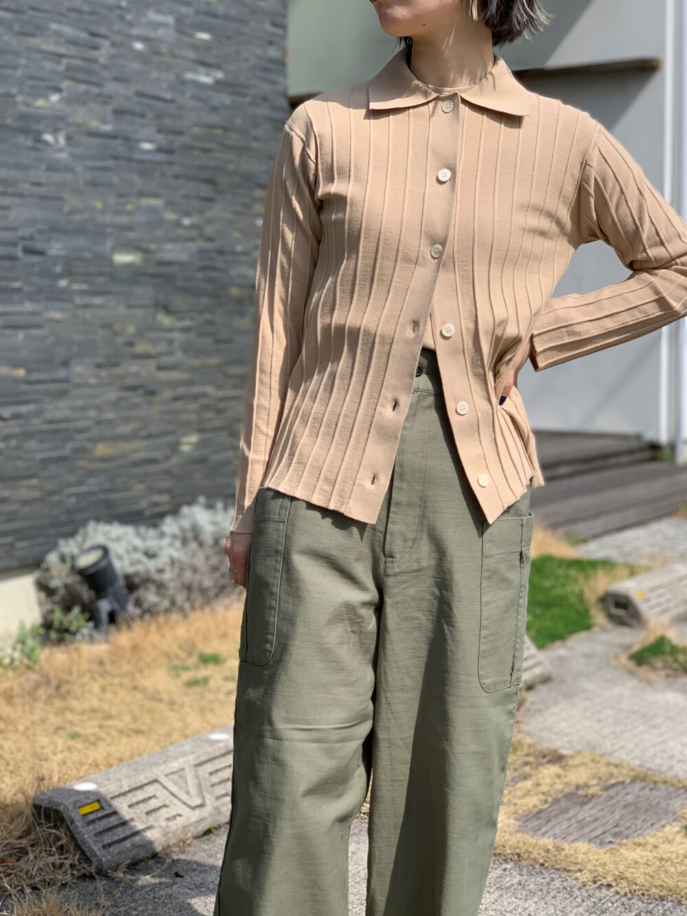 グリーン系のパンツ、ベージュ系のニット/セーターを着用したレディースの春コーディネートの3枚目の写真