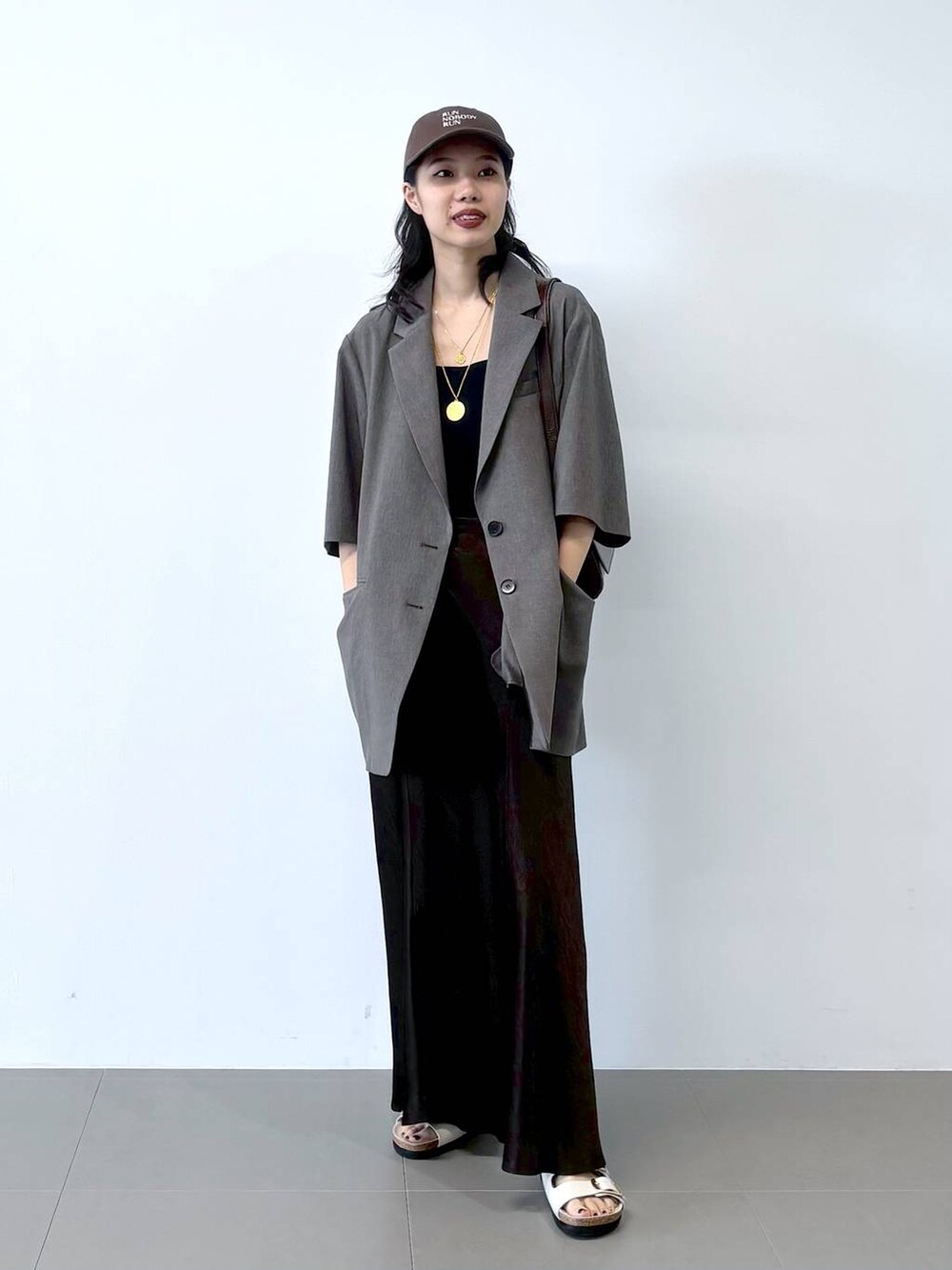 ホワイト系のサンダル、ブラック系のキャミソール、グレー系のテーラードジャケットを着用したレディースの春コーディネートの2枚目の写真