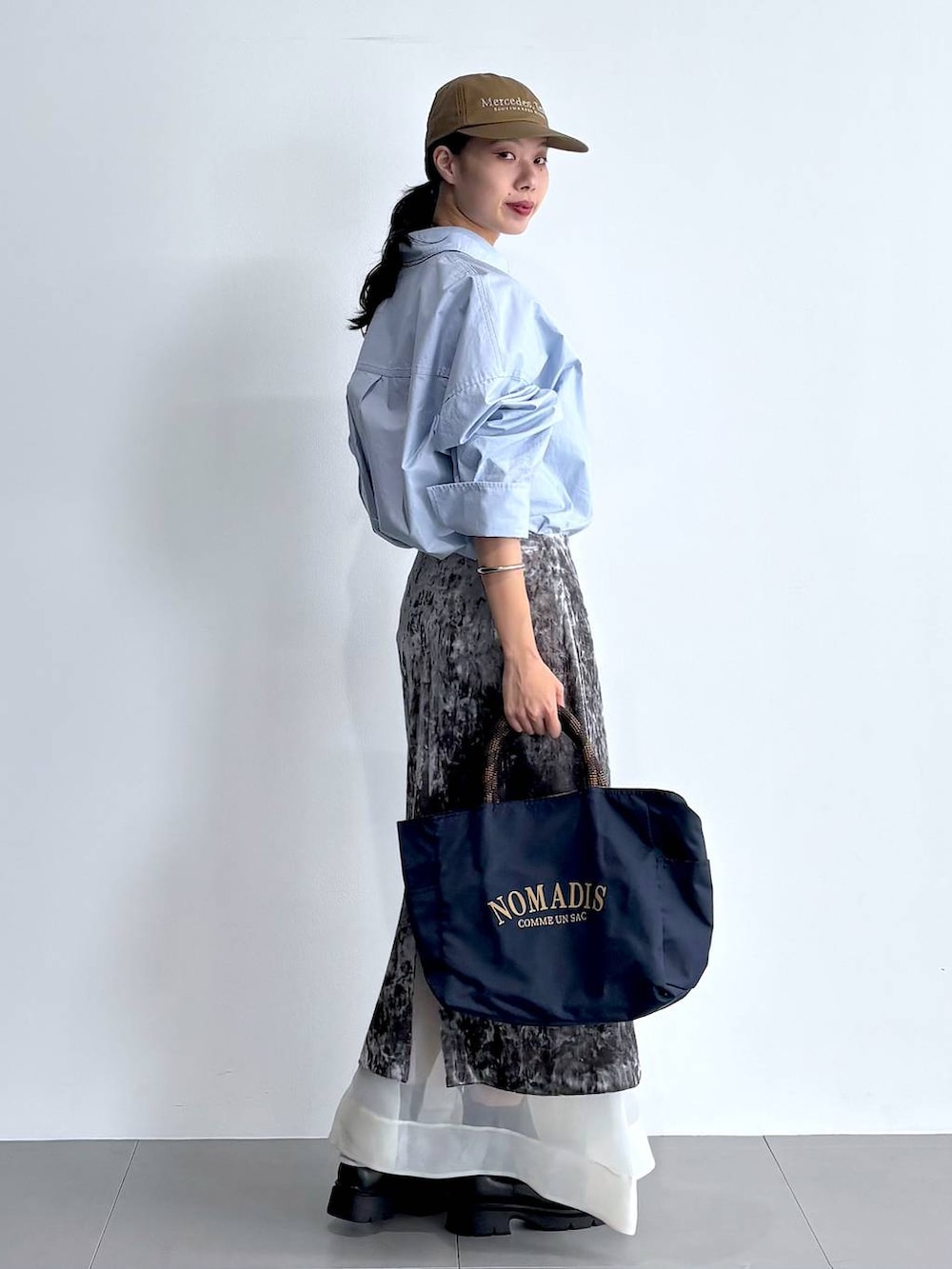 ブラック系のブーツ、グレー系のスカート、ブルー系のトートバッグを着用したレディースの秋コーディネートの3枚目の写真