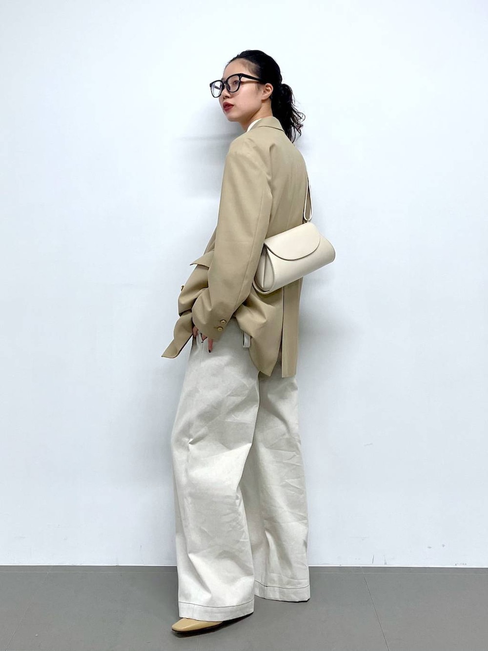 ホワイト系のショルダーバッグ、ベージュ系のテーラードジャケット、グレー系のサロペット/オーバーオールを着用したレディースの冬コーディネートの3枚目の写真
